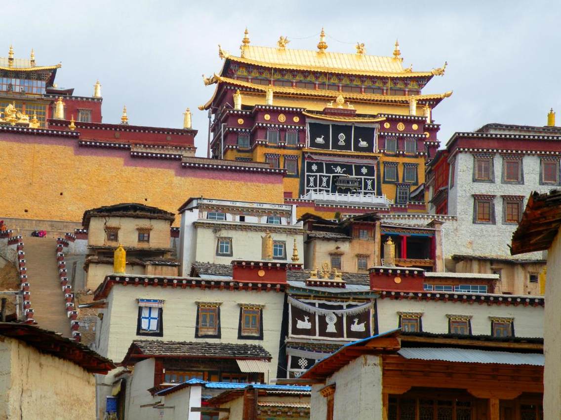 松赞林寺门口，穿着藏服的妇女在兜售着生意，或牵着藏獒要与你合影的，或要做导游讲解的，或穿着藏服骑牦牛拍照的，整条街上商业气息很浓。