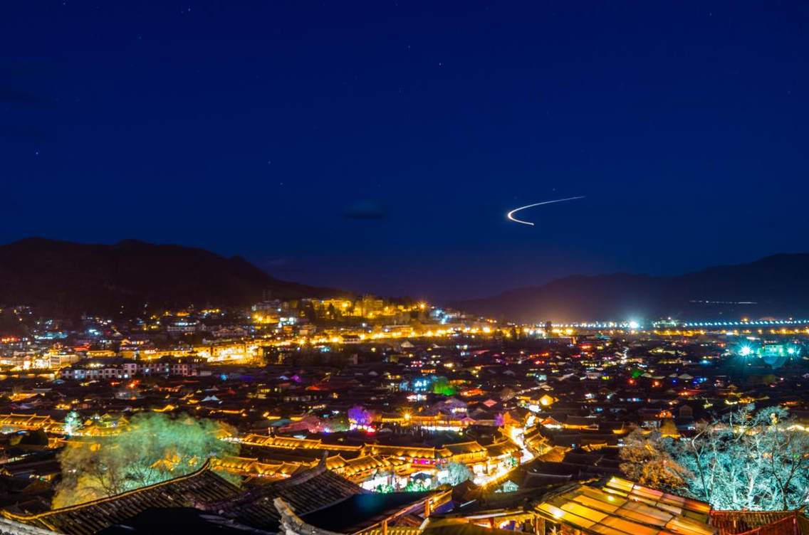 狮子山上拍大研古镇夜景,天空飞机正好划出一道弧线