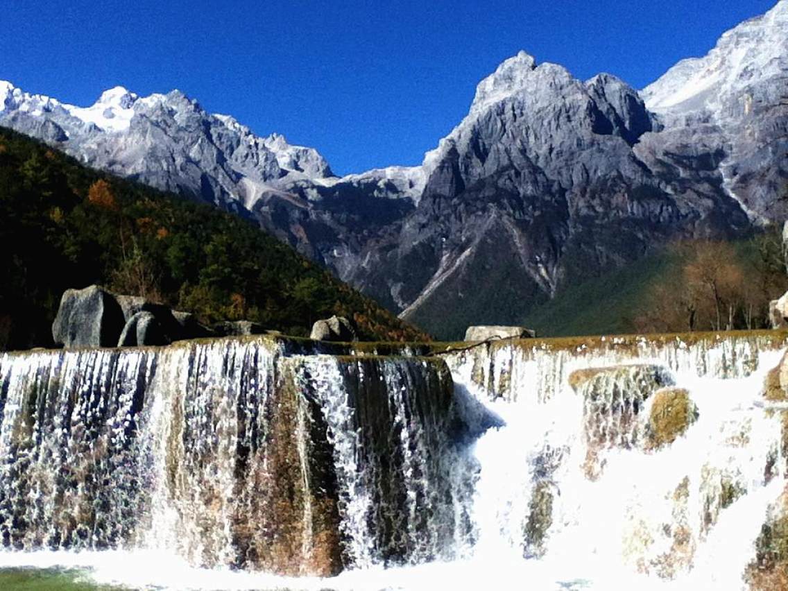中国云南丽江，蓝月亮谷，白水河瀑布和玉龙雪山。照片摄影图片_ID:317353987-Veer图库