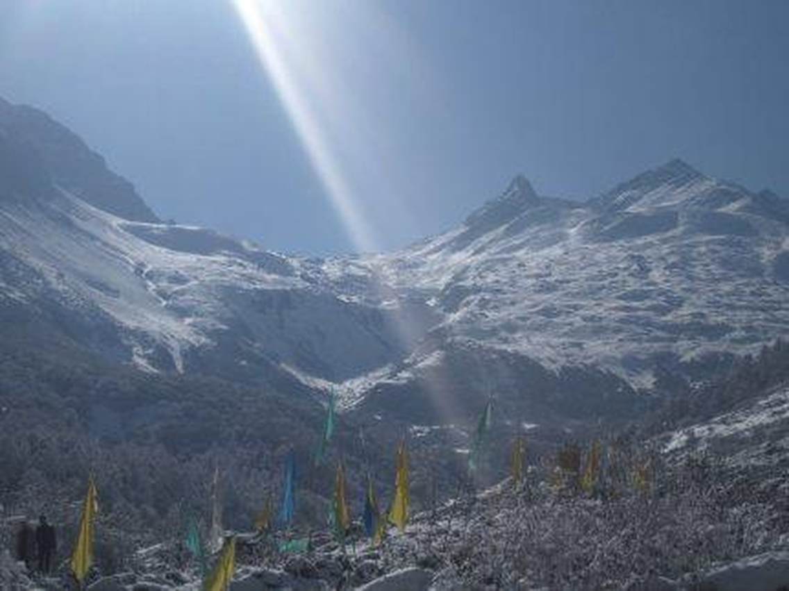 远处的高山在阳光的照射下略显模糊，近处的树在雪的覆盖下别有风韵，色彩不同的旗子代表人们对大山的头顶的太阳，洒下一缕阳光——一米阳光,便是天堂.