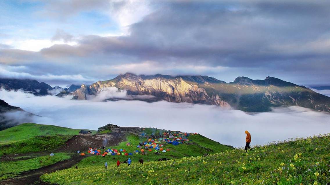 这张照片拍摄于四川阿坝州茂县九顶山，7月初，鲜花盛开，头一天下了雨，日出的时候难得的一丝光线。山下扎满了五颜六色的帐篷成了这清晨的美丽点缀。