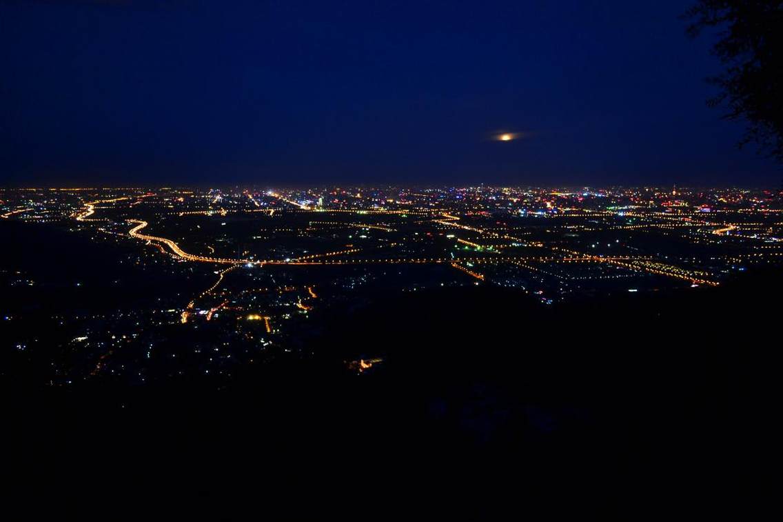 晴朗的夏夜，香山香炉峰上，北京城璀璨的灯火犹如光的海洋，一轮圆月从薄云中升起